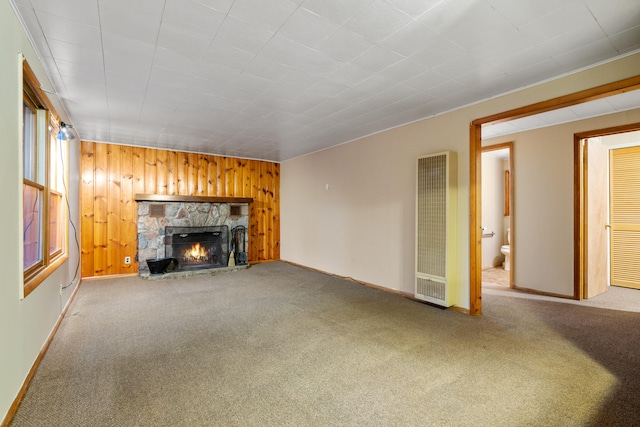 unfurnished living room featuring carpet, a fireplace, and wood walls