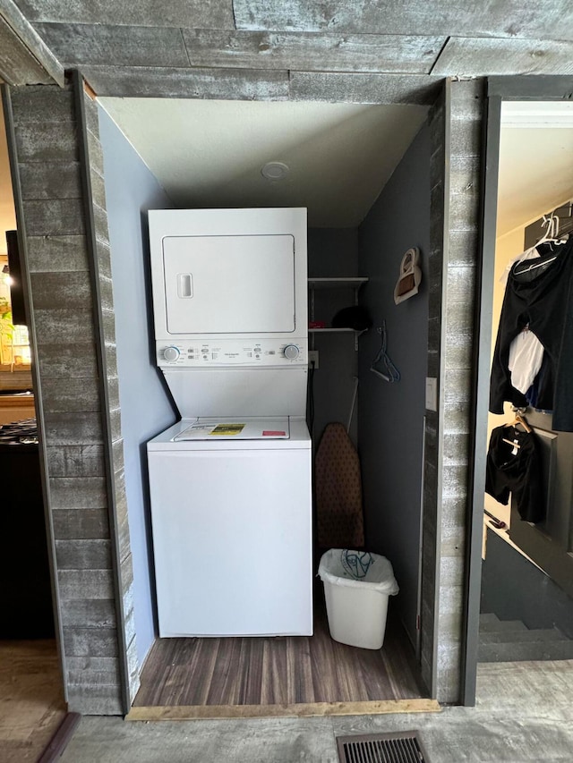 washroom featuring dark hardwood / wood-style floors and stacked washer and clothes dryer