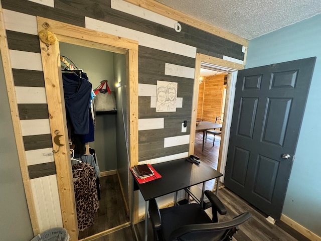 interior space with a textured ceiling, dark hardwood / wood-style flooring, and wood walls