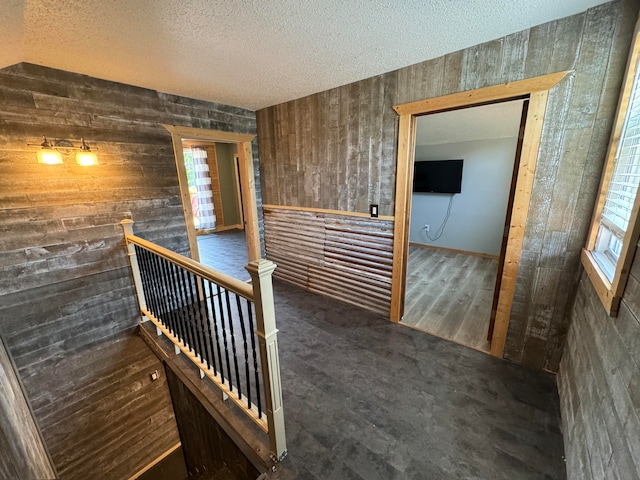 corridor with a wealth of natural light, dark hardwood / wood-style floors, and a textured ceiling