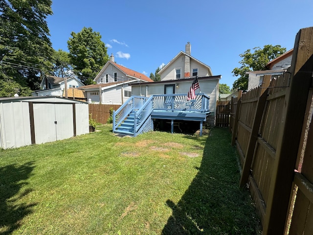 rear view of house featuring a yard, a storage unit, and a deck