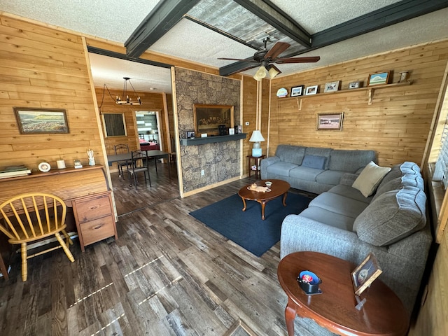 living room with dark wood-type flooring, ceiling fan with notable chandelier, wooden walls, a textured ceiling, and beam ceiling