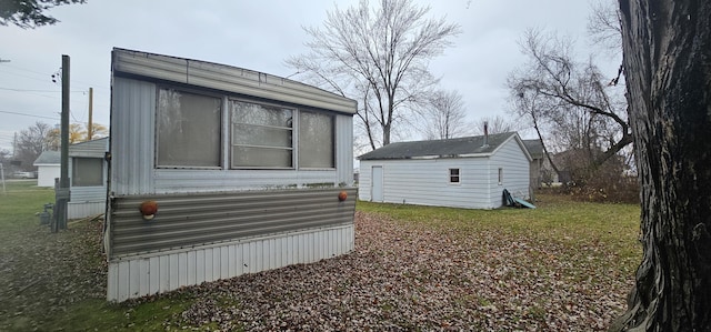 view of side of home featuring a lawn and an outbuilding