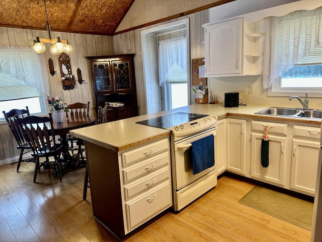 kitchen featuring kitchen peninsula, vaulted ceiling, sink, decorative light fixtures, and white electric stove