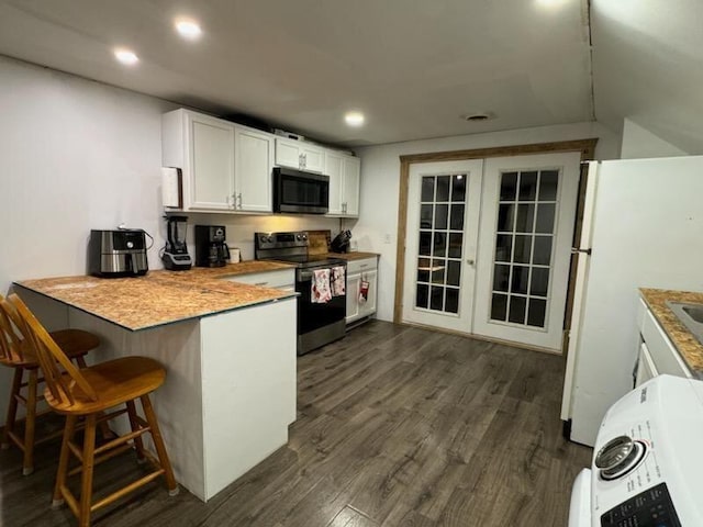 kitchen featuring dark wood-type flooring, stainless steel appliances, kitchen peninsula, a breakfast bar area, and white cabinets