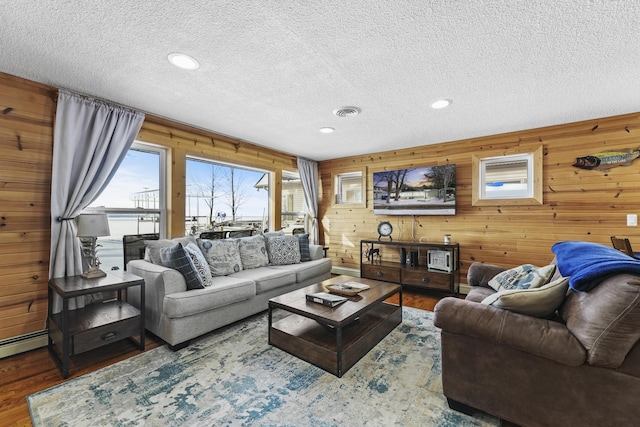 living room featuring dark hardwood / wood-style floors, a textured ceiling, wooden walls, and a baseboard radiator