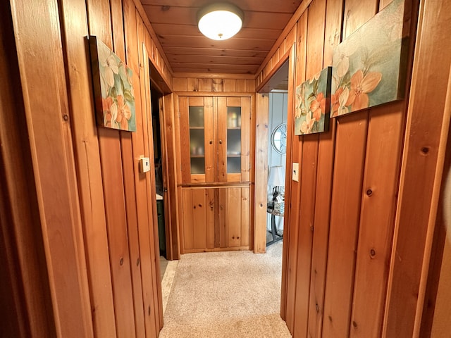 hallway featuring wood walls, light colored carpet, and wood ceiling