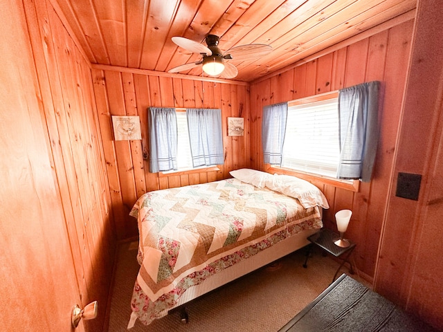 carpeted bedroom featuring ceiling fan, wood walls, and wooden ceiling