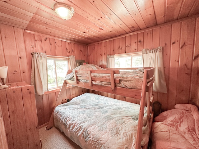 carpeted bedroom with wood walls, wooden ceiling, and multiple windows