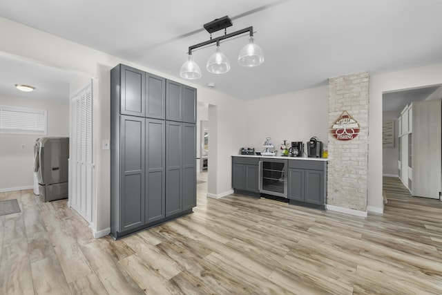 kitchen featuring gray cabinetry, hanging light fixtures, light wood-type flooring, washer / dryer, and beverage cooler