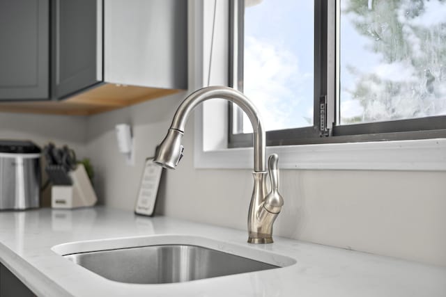 room details featuring gray cabinets, light stone counters, and sink