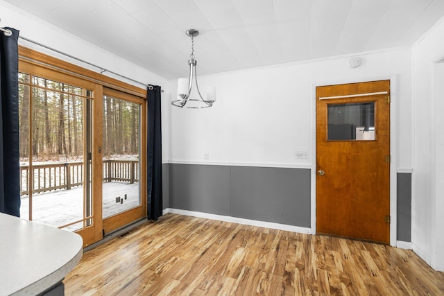 unfurnished dining area with hardwood / wood-style floors, an inviting chandelier, and crown molding