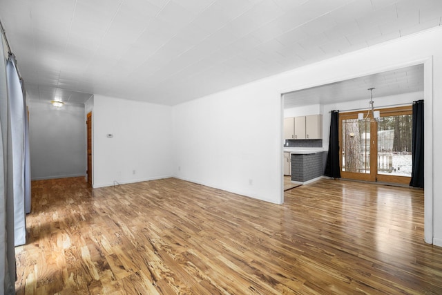 unfurnished living room with hardwood / wood-style flooring and a notable chandelier