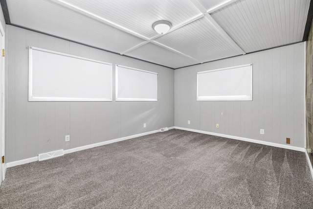 carpeted empty room featuring wood walls