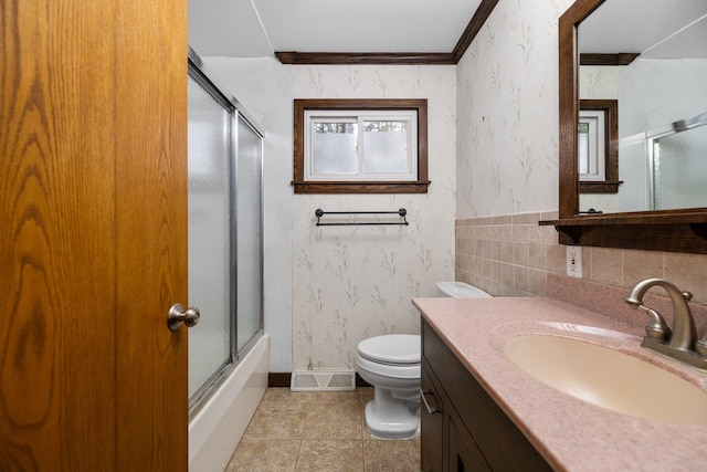 full bathroom with tile patterned floors, combined bath / shower with glass door, toilet, vanity, and ornamental molding