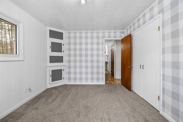 carpeted spare room with ornamental molding and wood walls