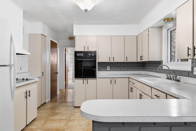 kitchen with decorative backsplash, sink, white refrigerator, white cabinets, and black oven