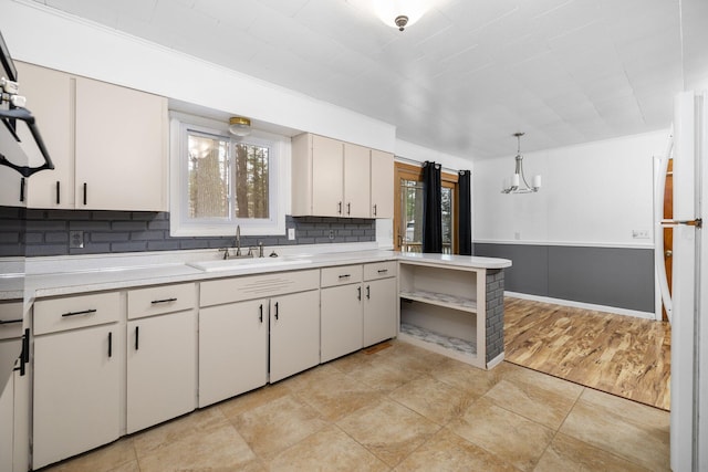 kitchen featuring white cabinetry, white refrigerator, backsplash, light hardwood / wood-style floors, and pendant lighting