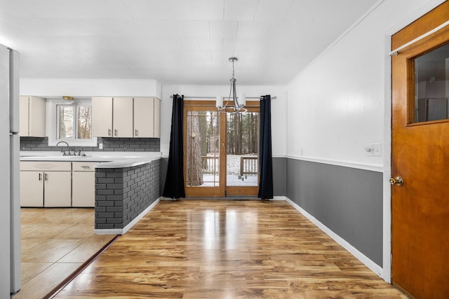 kitchen featuring decorative light fixtures, plenty of natural light, white cabinetry, and light wood-type flooring