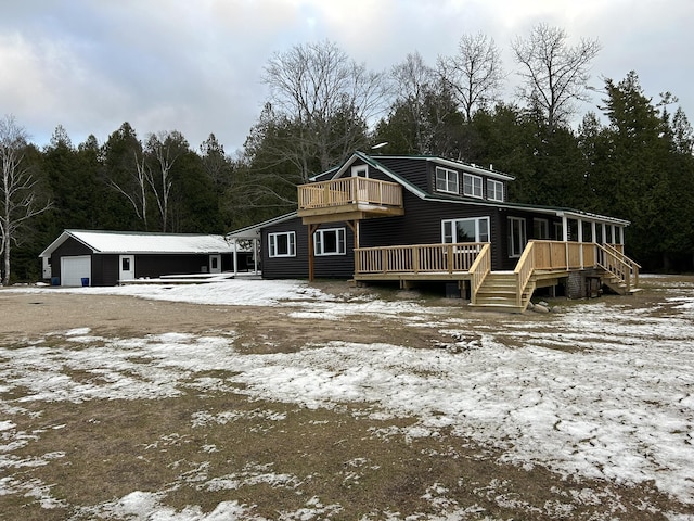 snow covered rear of property featuring an outdoor structure and a garage