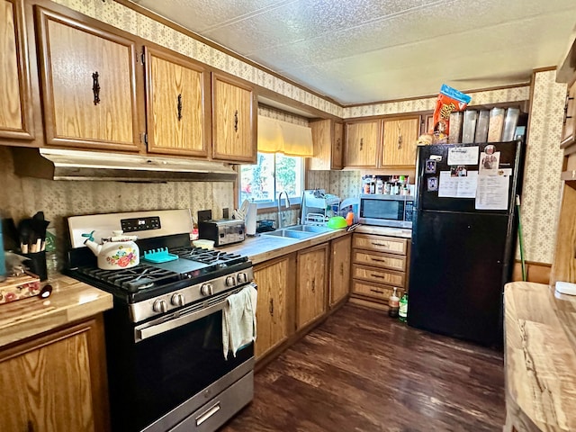 kitchen with appliances with stainless steel finishes, a textured ceiling, dark hardwood / wood-style floors, and sink