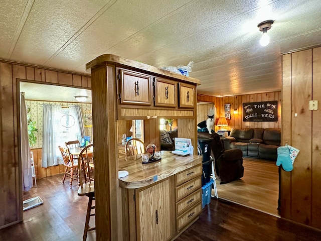 kitchen featuring a textured ceiling, dark wood-type flooring, and wooden walls