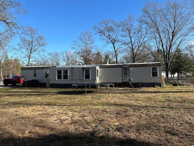 back of property with a trampoline and a lawn