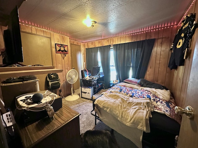 carpeted bedroom with a textured ceiling and wooden walls