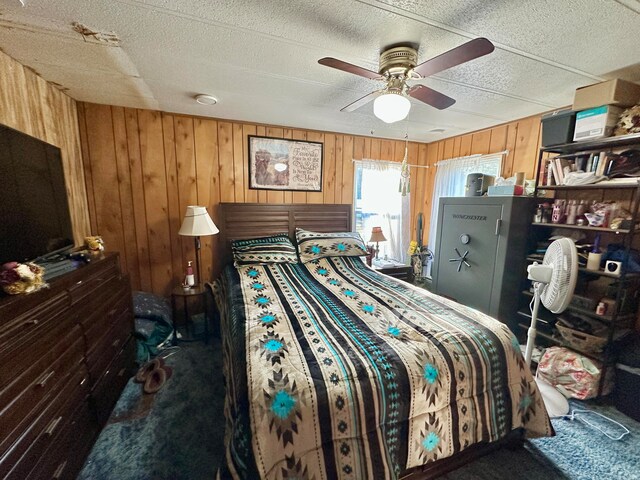 bedroom with a textured ceiling, carpet floors, ceiling fan, and wood walls