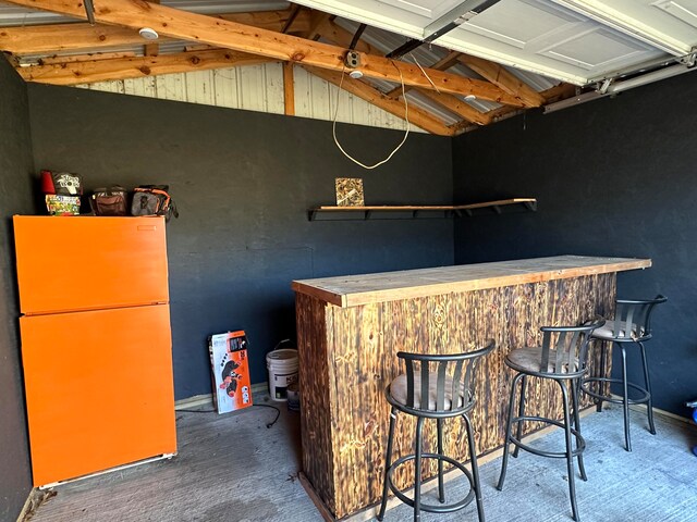 bar with white refrigerator and lofted ceiling