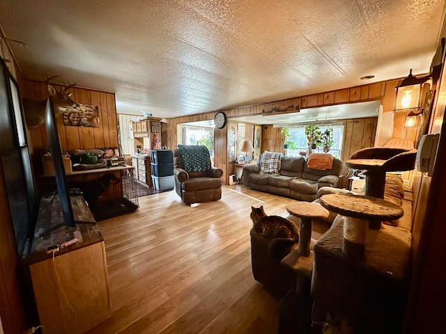 living room featuring wooden walls, a textured ceiling, and light wood-type flooring