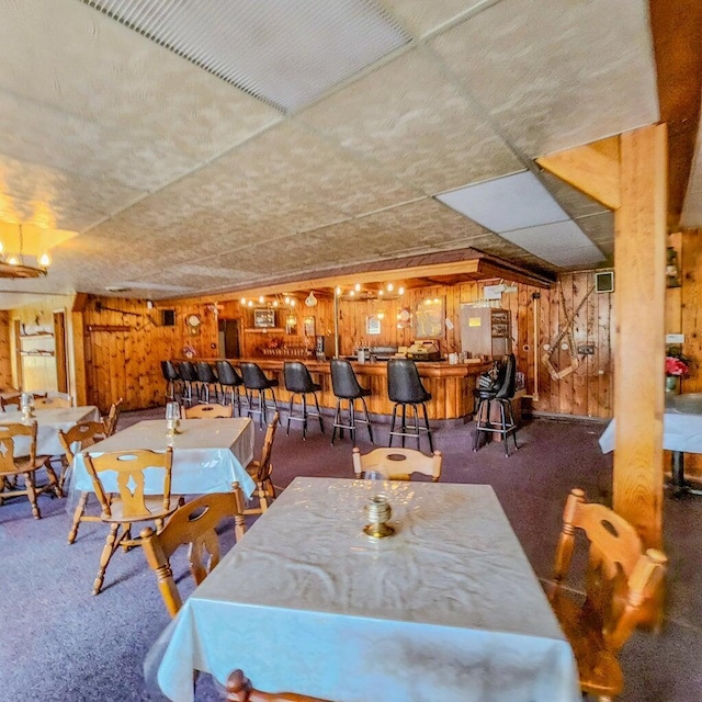 carpeted dining space with wood walls