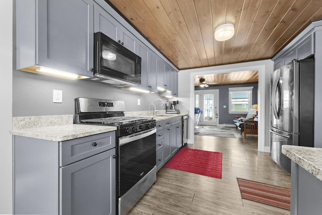 kitchen with appliances with stainless steel finishes, light wood-type flooring, gray cabinetry, ceiling fan, and wooden ceiling