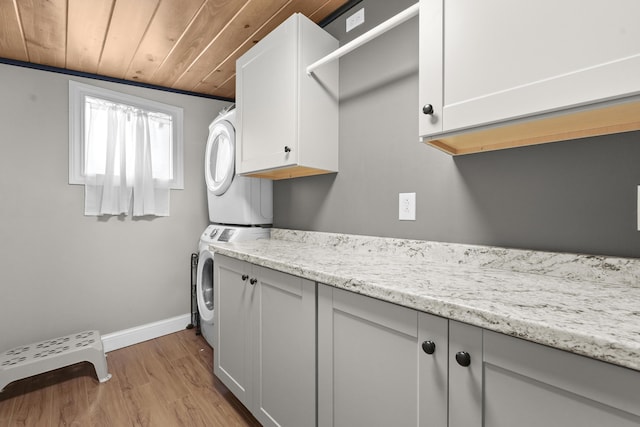 laundry area with cabinets, wooden ceiling, light wood-type flooring, stacked washer / drying machine, and ornamental molding