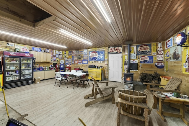 interior space featuring light wood-type flooring, wooden walls, and a wood stove