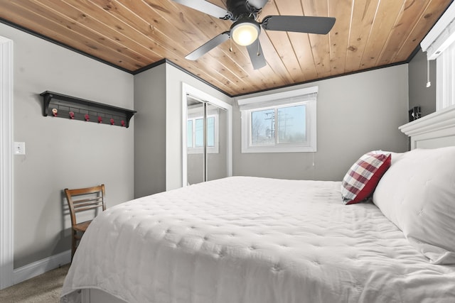 carpeted bedroom featuring ceiling fan, wood ceiling, crown molding, and a closet