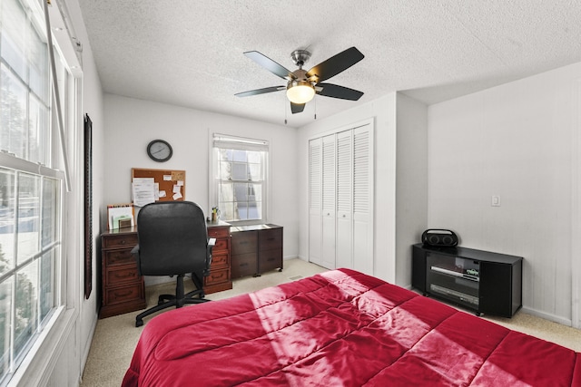 carpeted bedroom with a textured ceiling, a closet, and ceiling fan