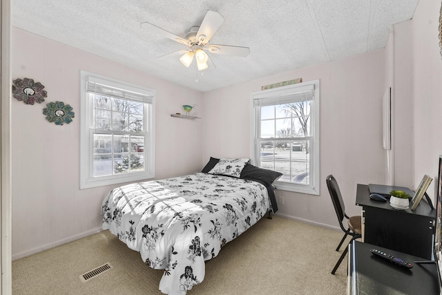 bedroom featuring light carpet, a textured ceiling, and ceiling fan