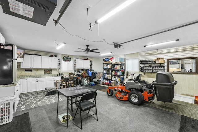 garage with a garage door opener, a workshop area, stainless steel refrigerator, and ceiling fan