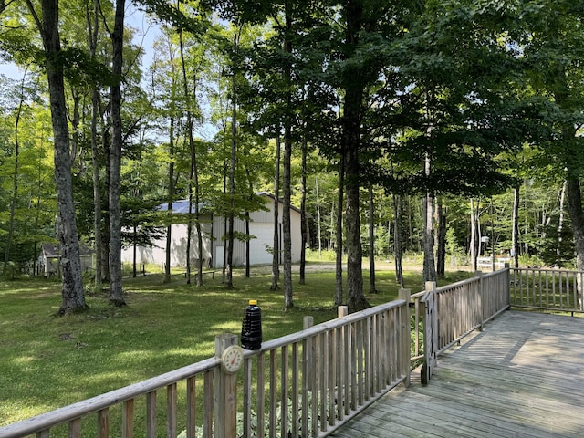 wooden terrace featuring an outdoor structure, a garage, and a yard