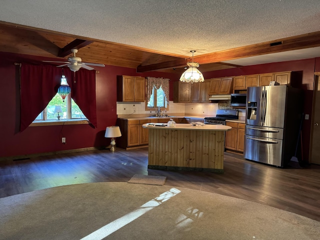 kitchen with beamed ceiling, stainless steel appliances, a kitchen island, and dark wood-type flooring