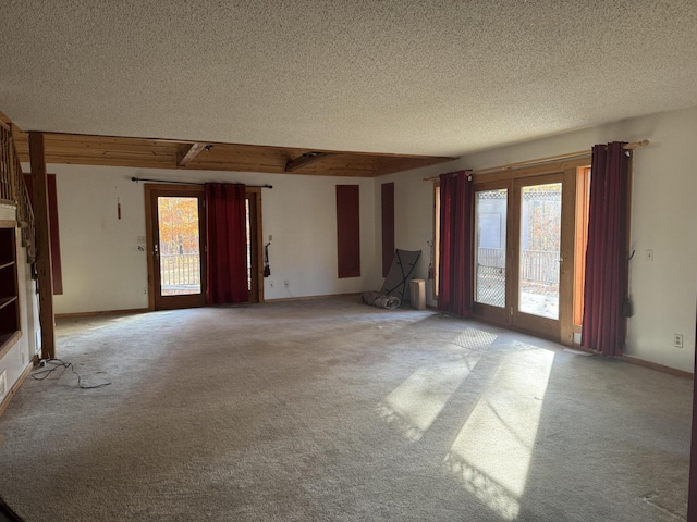 unfurnished living room with a textured ceiling, carpet floors, and a wealth of natural light