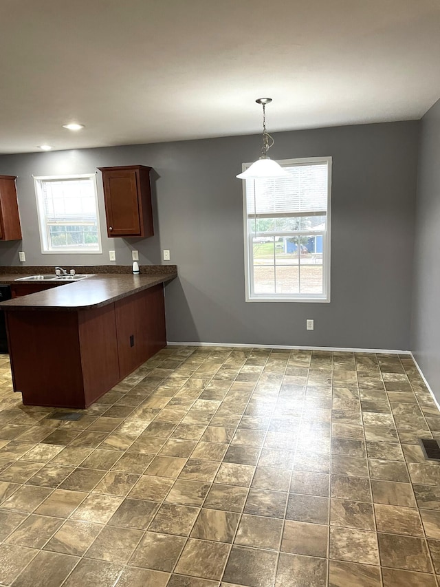 kitchen featuring black dishwasher, sink, kitchen peninsula, and hanging light fixtures