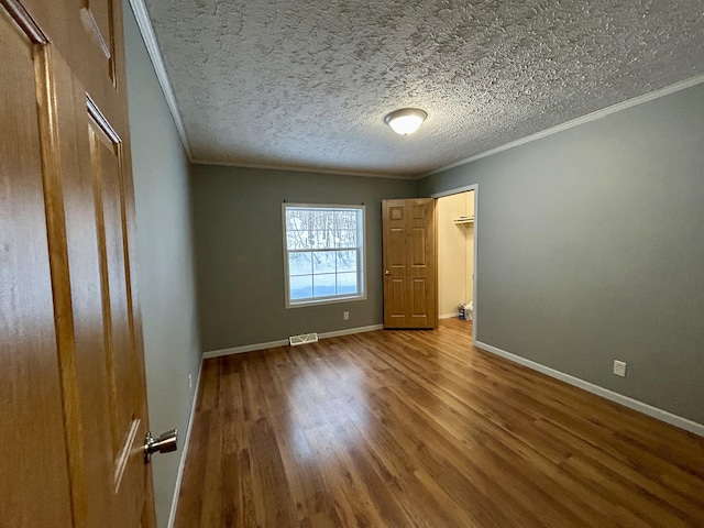 unfurnished bedroom featuring hardwood / wood-style floors, crown molding, and a textured ceiling