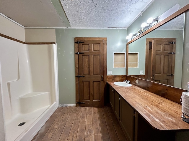 bathroom with walk in shower, vanity, a textured ceiling, and hardwood / wood-style flooring