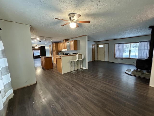 kitchen featuring a kitchen bar, ceiling fan, a textured ceiling, dark hardwood / wood-style flooring, and kitchen peninsula