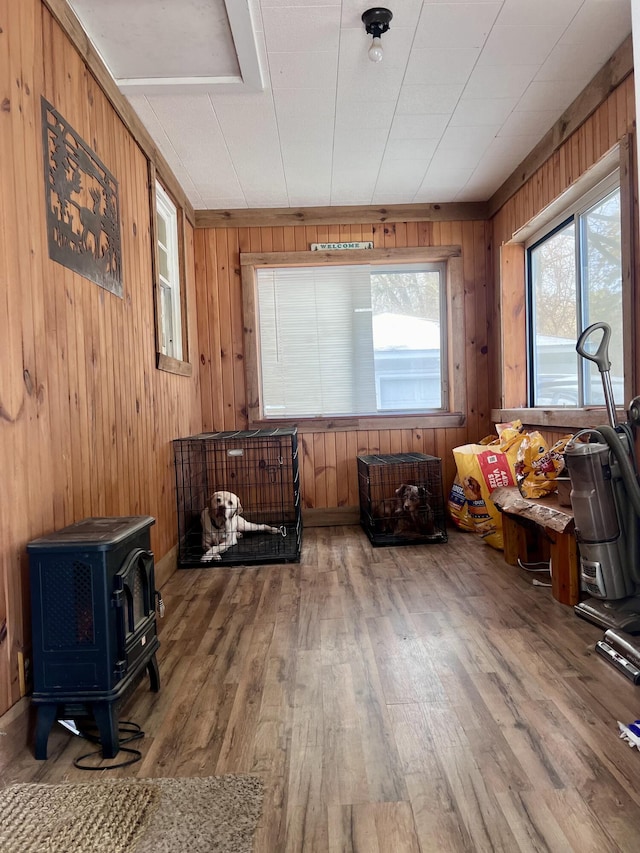 miscellaneous room featuring wood-type flooring, a wood stove, and wood walls