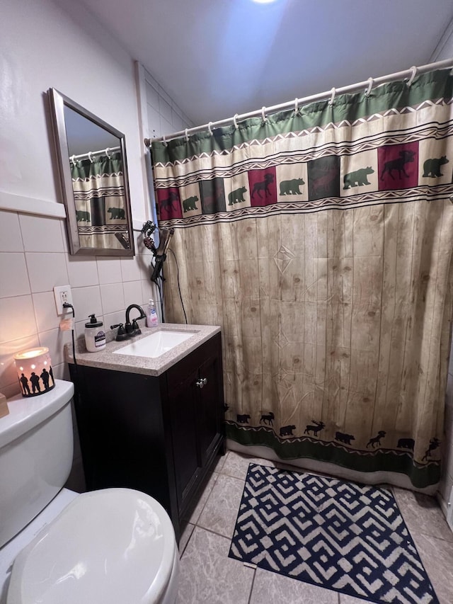 bathroom with vanity, backsplash, tile patterned floors, toilet, and tile walls