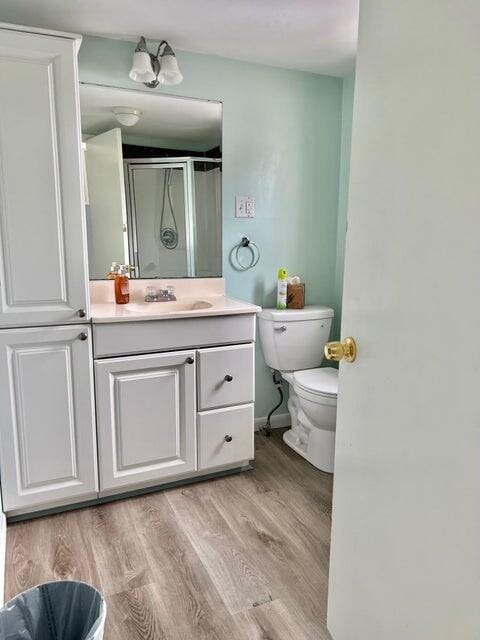 bathroom featuring vanity, hardwood / wood-style flooring, toilet, and an enclosed shower