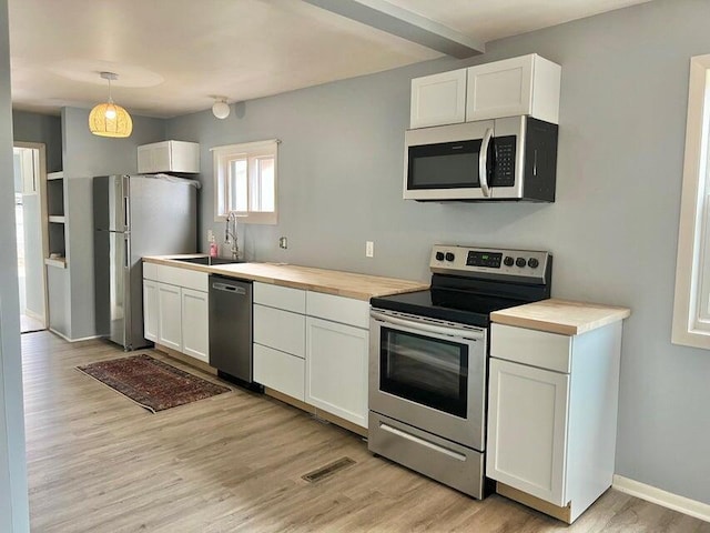 kitchen with white cabinets, hanging light fixtures, and appliances with stainless steel finishes